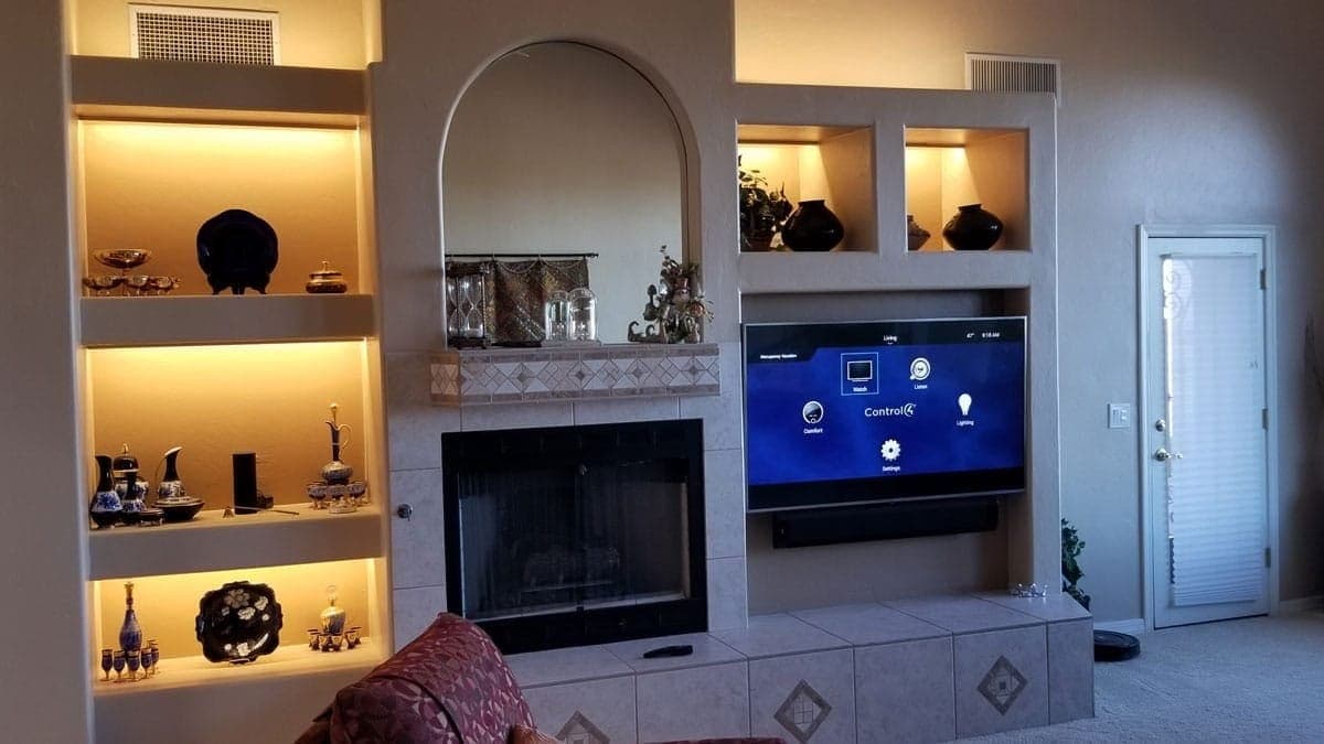 Fireplace wall with lit display niches and an integrated screen above the hearth