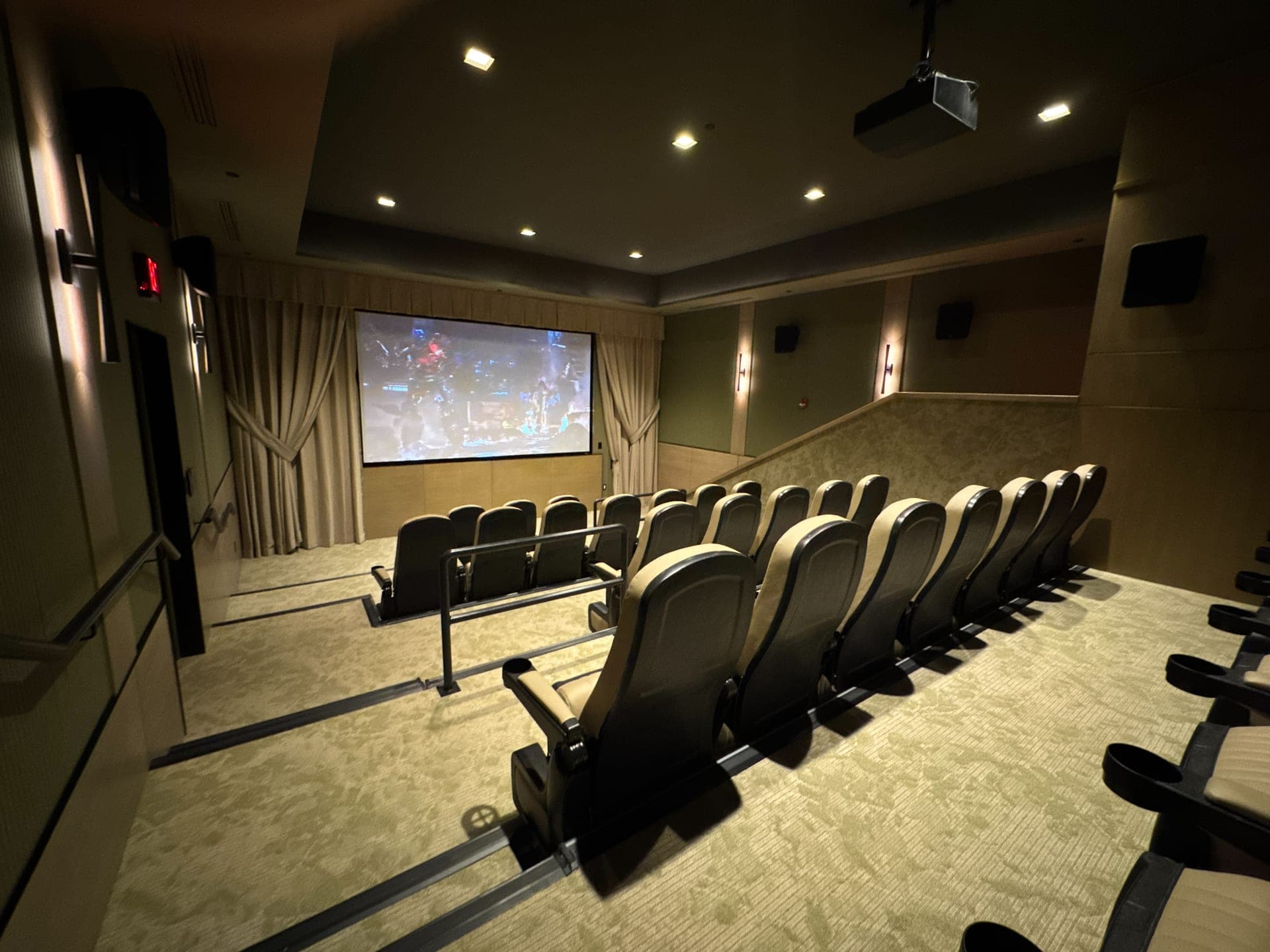 Dedicated theater room with black leather recliners and a front projection screen