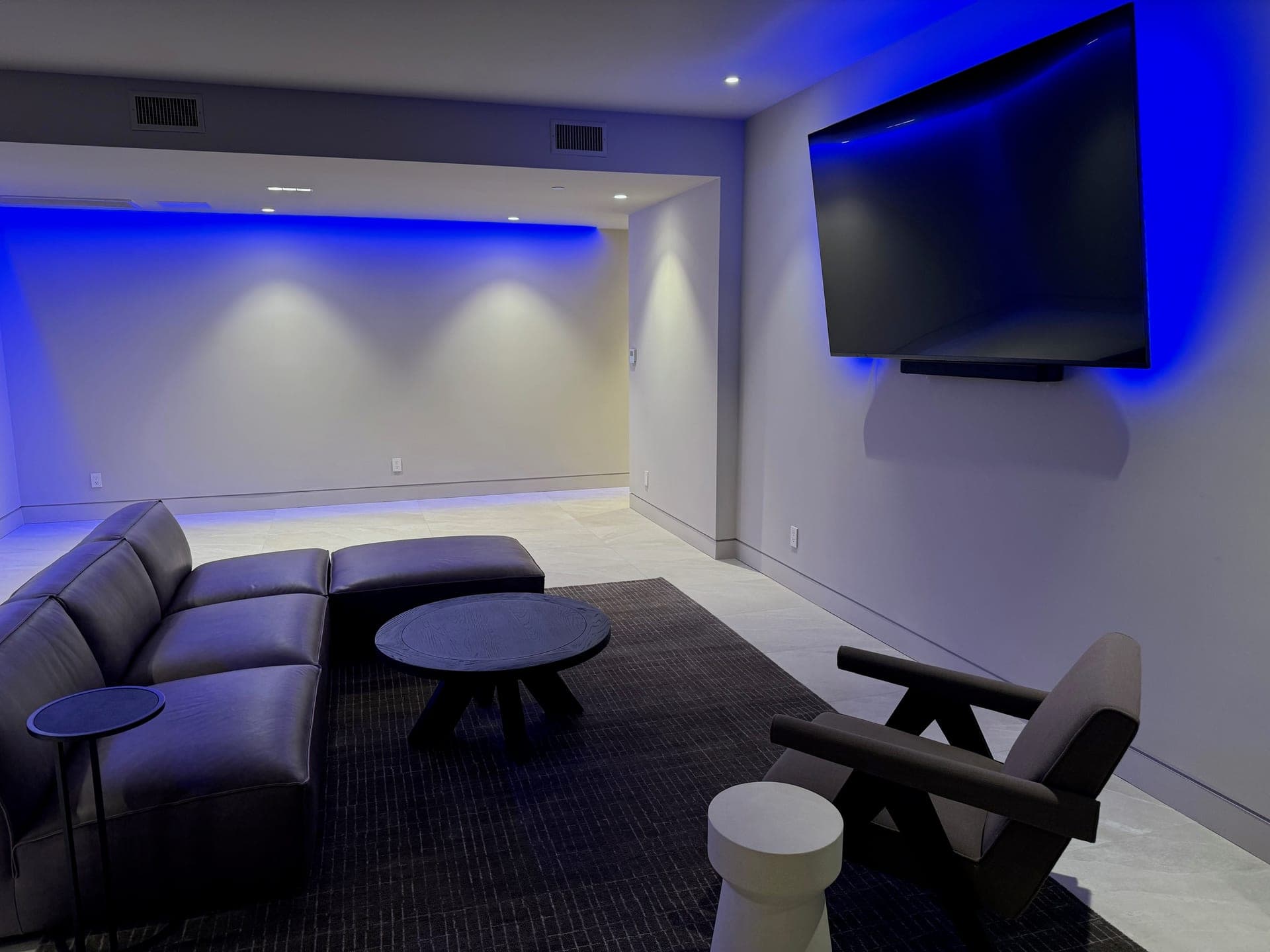 Lounge and media room with blue accent lighting and a wall-mounted display