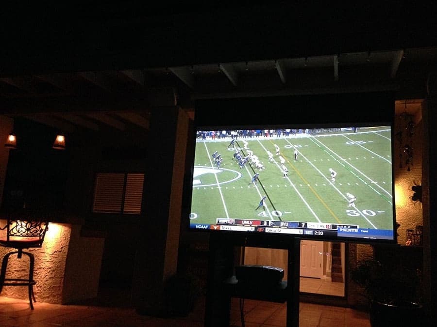 Media room with a large display showing a football game and in-ceiling surround speakers