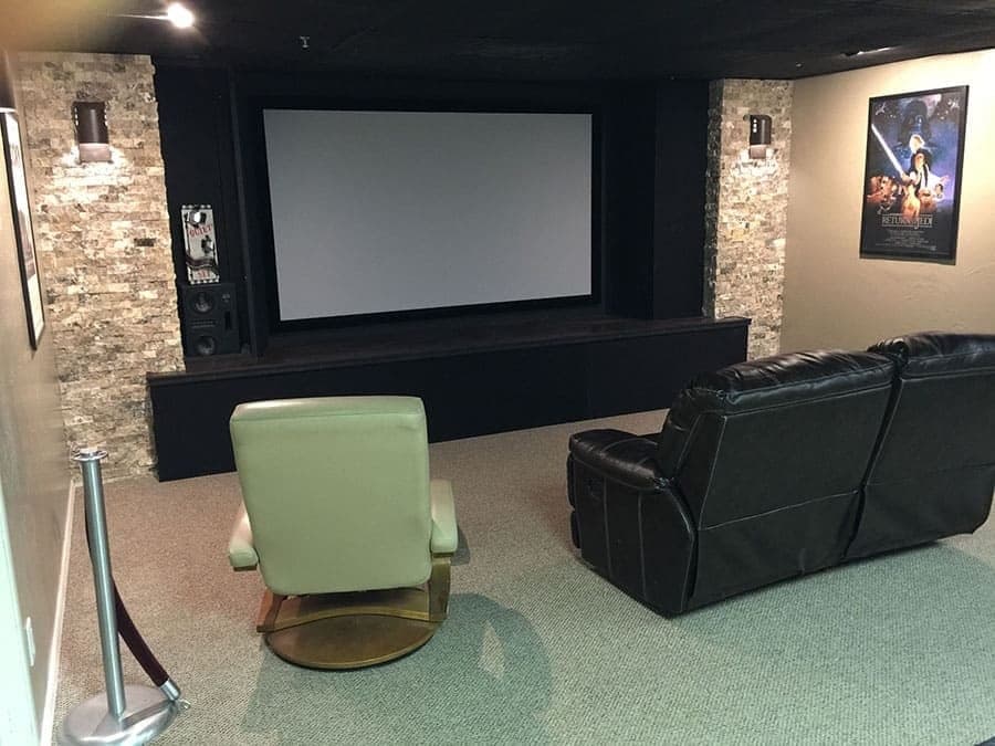 Media room with a drop-down projection screen against a stone accent wall